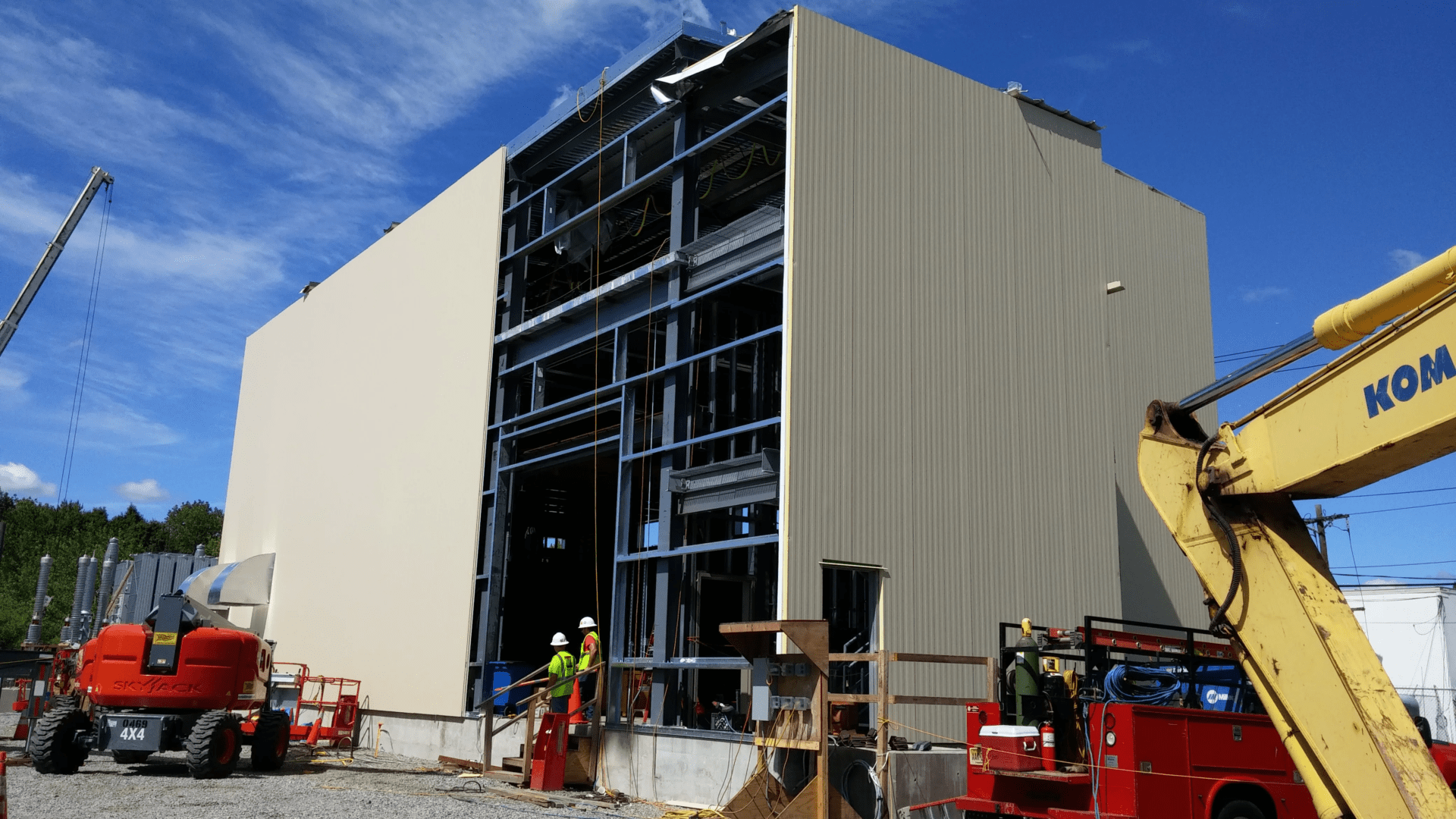 two men with hard hats standing beside a building under construction